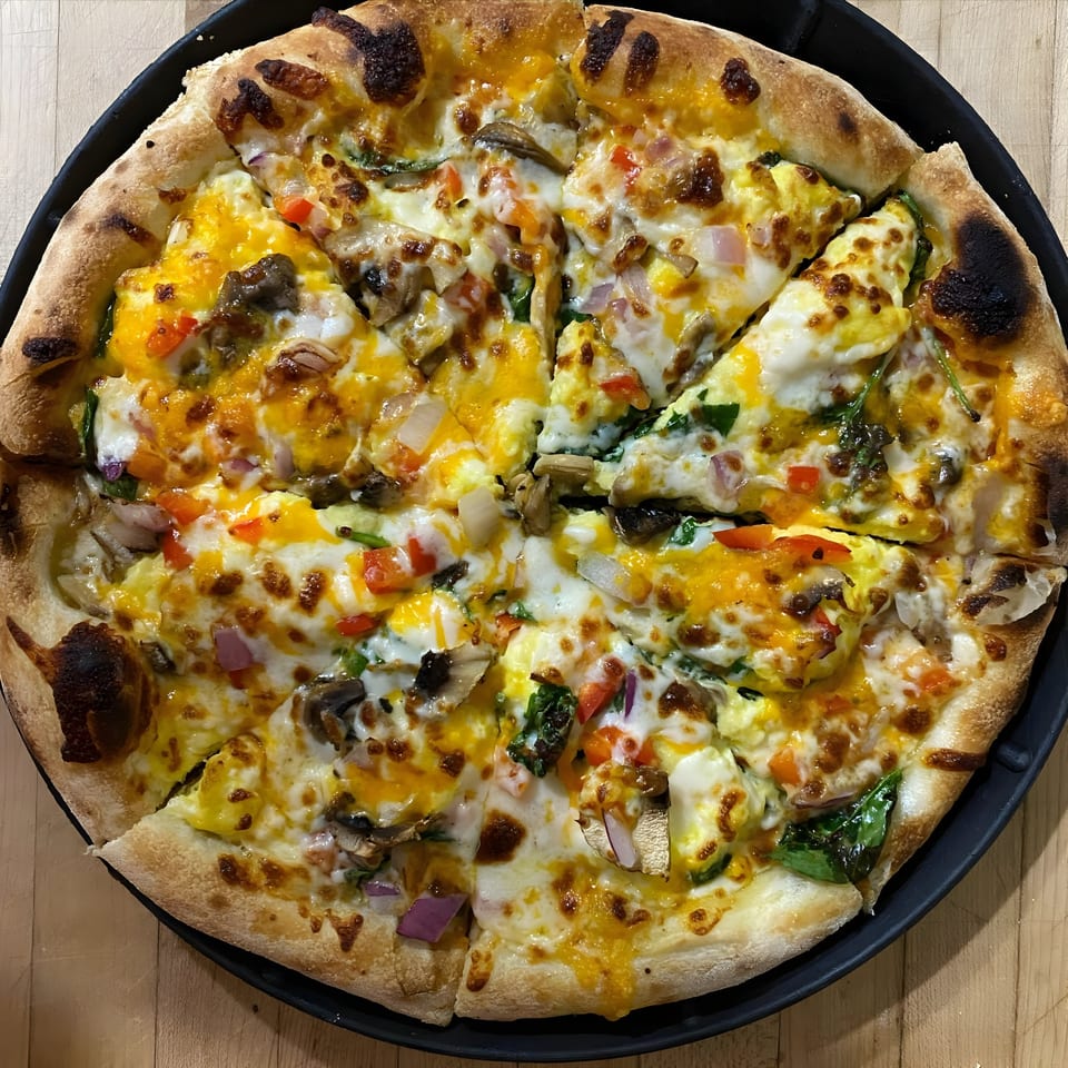 A freshly baked Bodacious Pizza with scrambled eggs, cheese, mushrooms, red onions, and spinach.